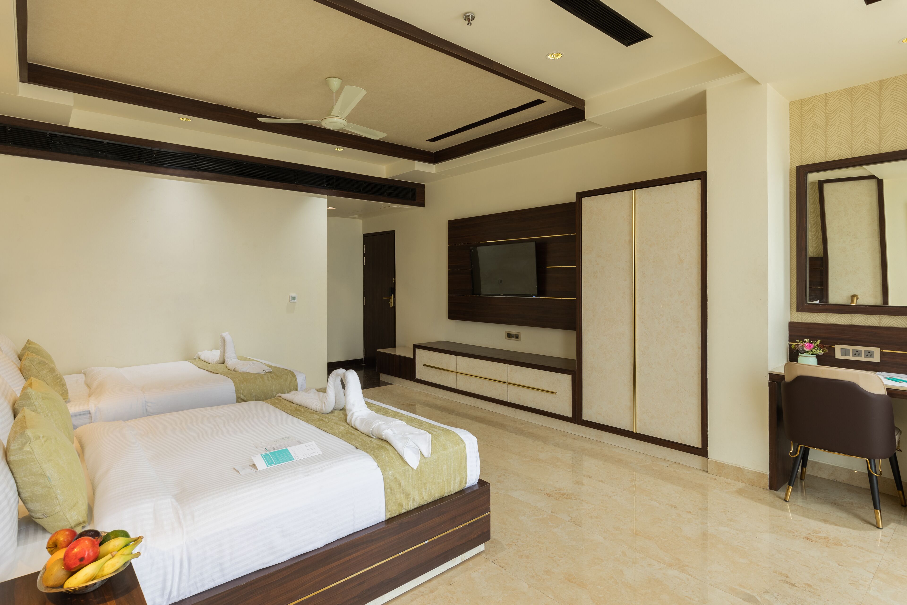 A hotel room with a large bed, a desk, a television, and a wardrobe.