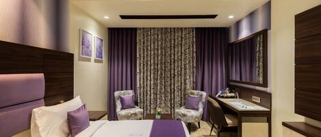 Una habitación de hotel con una cama, dos sillas, un escritorio y un espejo grande.