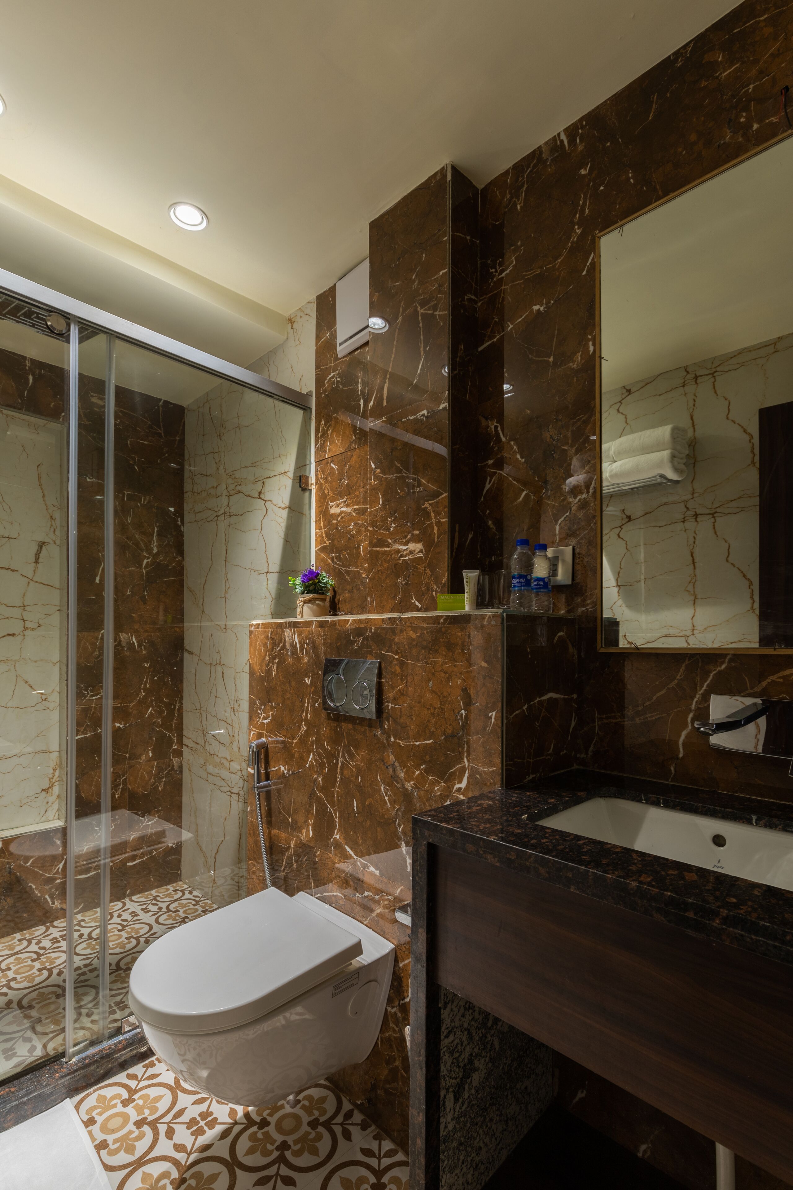 A modern bathroom with a glass-enclosed shower, a marble vanity, and a large mirror.