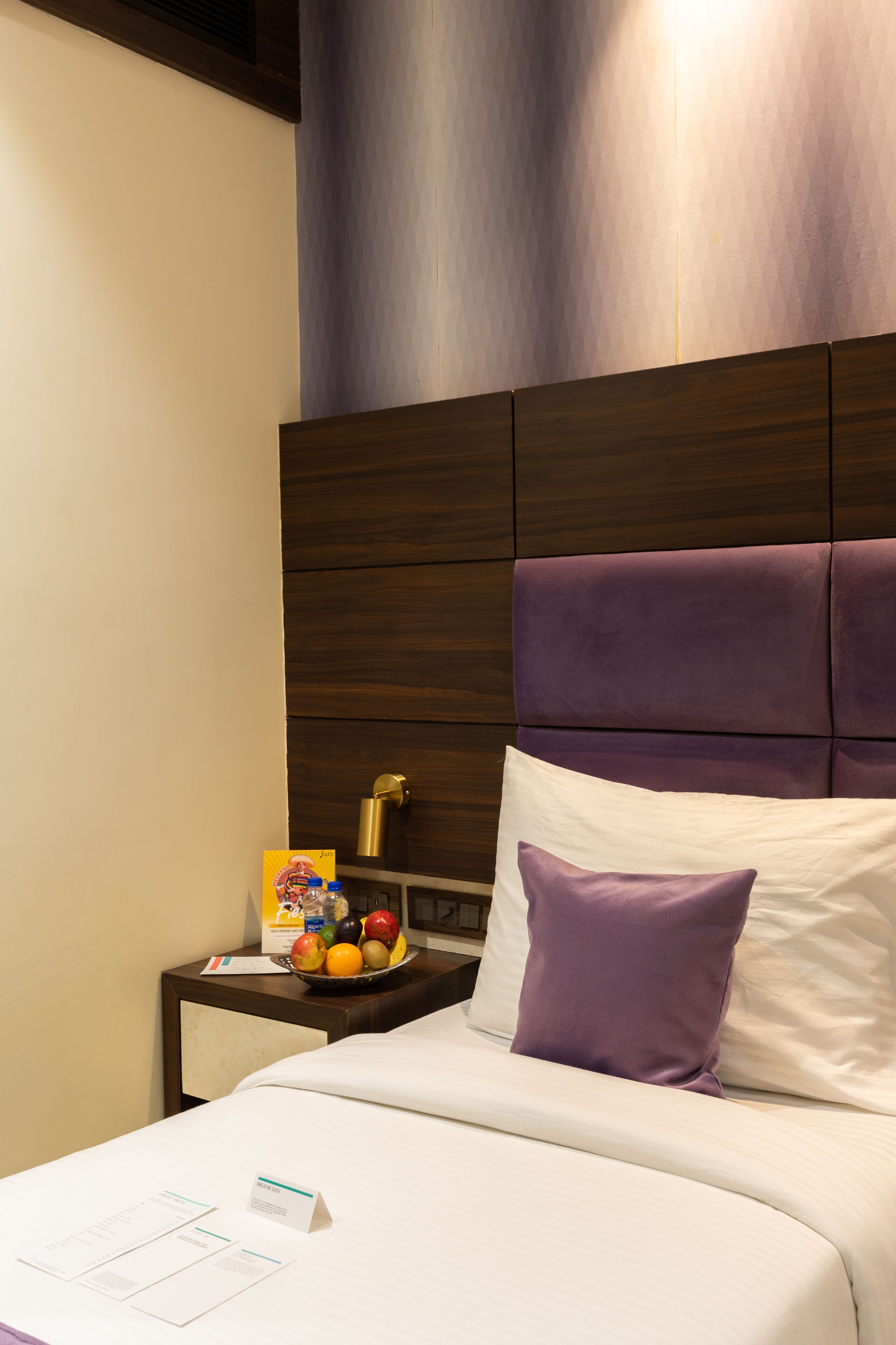Una habitación de hotel con una cama, una mesita de noche y un frutero.