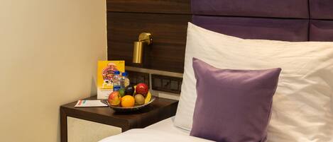 Una habitación de hotel con una cama, una mesita de noche y un frutero.