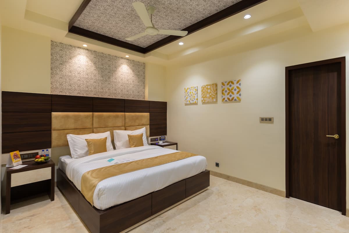A modern bedroom with a large bed, a nightstand, a ceiling fan, and decorative wall art.