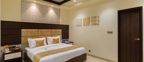A modern bedroom with a large bed, a nightstand, a ceiling fan, and decorative wall art.