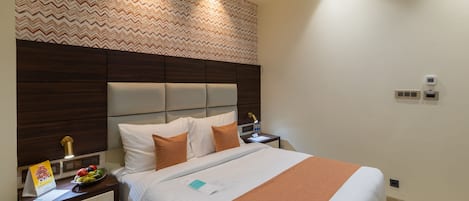 A hotel room with a bed, nightstands, a wall clock, and a patterned wallpaper.