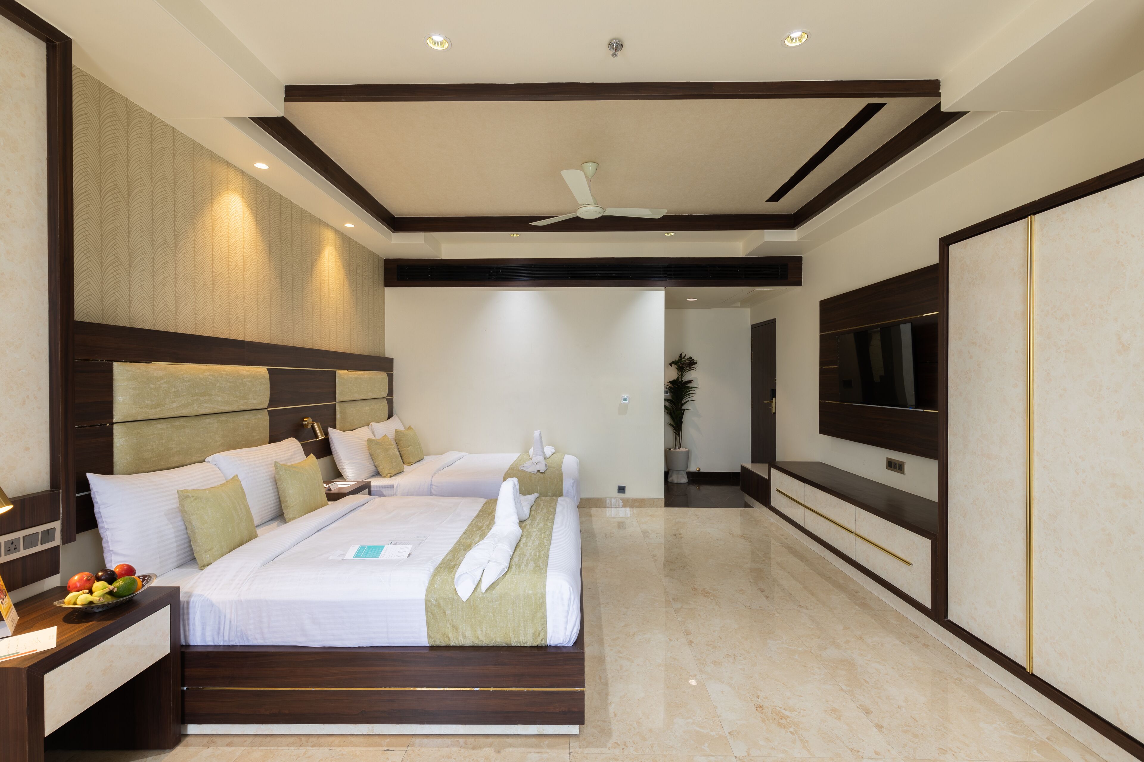 Una habitación de hotel moderna con una cama grande, un televisor de pantalla plana y un ventilador de techo.