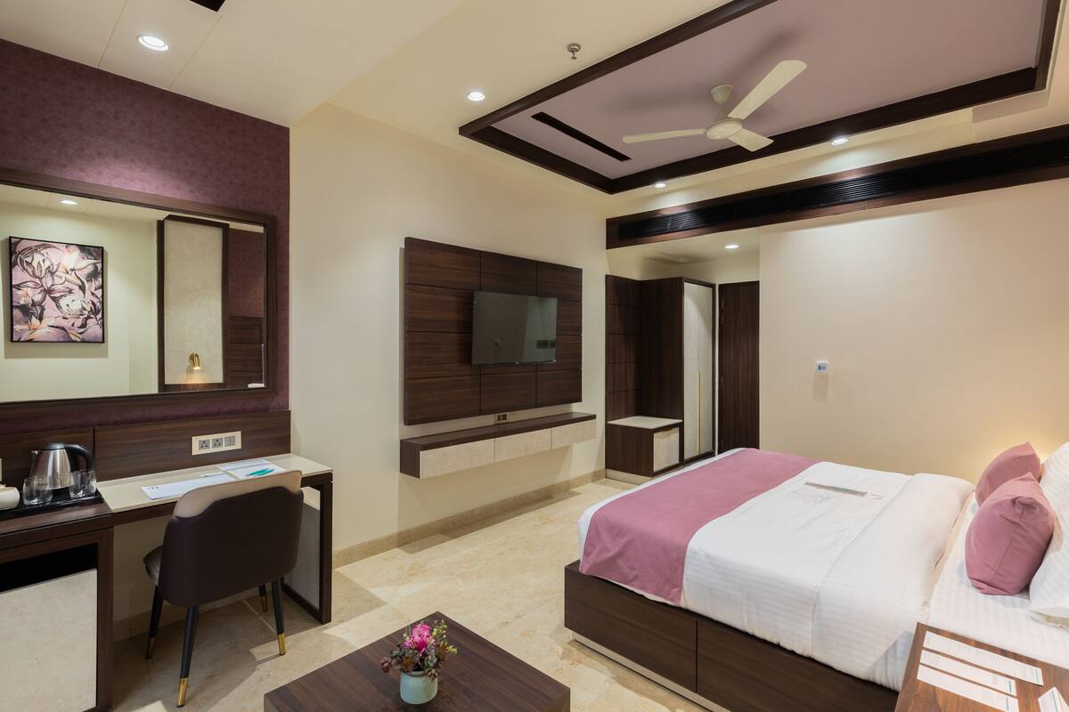 A modern hotel room with a desk, chair, bed, and a ceiling fan.