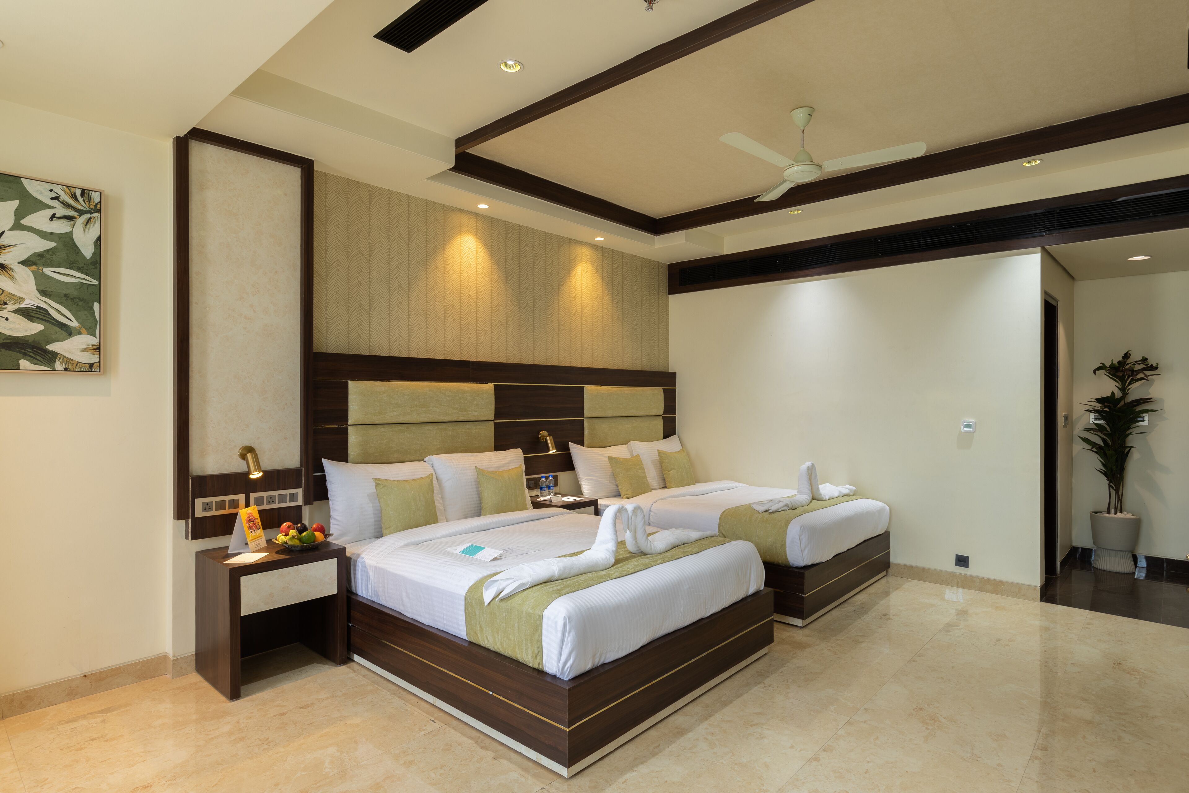 A hotel room with two beds, a nightstand, a wall-mounted artwork, and a ceiling fan.
