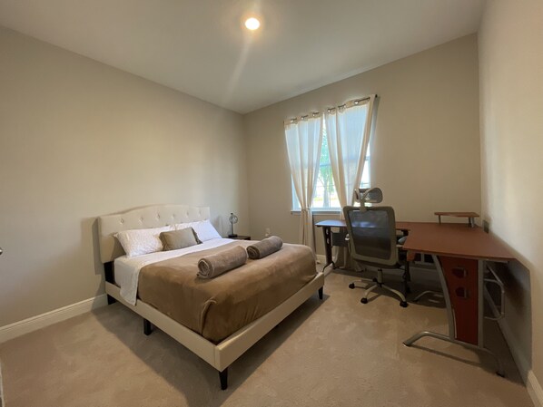 Un dormitorio con una cama, un escritorio y una silla.