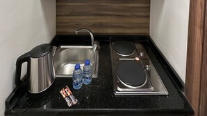 A compact kitchenette with a microwave, sink, kettle, and water bottles. - 2, Antica Jabalal-lwebdeh (Amman)