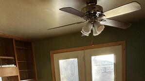 A dining area with a round table, four chairs, a ceiling fan, and a view through a glass door. - Cute Two Bedroom Cottage in Quiet Setting (Aberdeen)