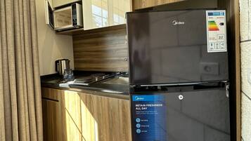 A kitchen with a black refrigerator, a microwave, and wooden cabinets.