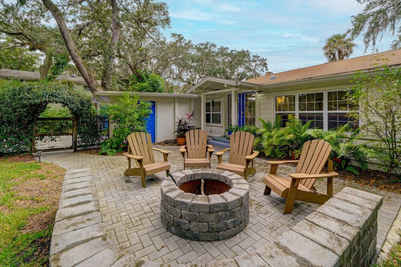 A patio with Adirondack chairs and a stone fire pit.