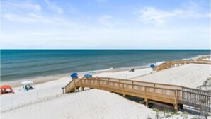 A beach with a wooden boardwalk, sandy beach, and umbrellas.
