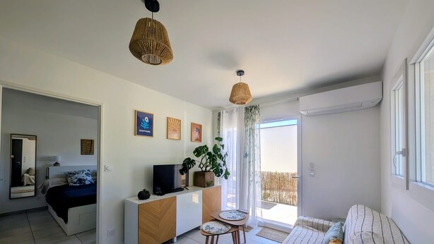 Un soggiorno moderno con divano, televisore su mobile in legno, tavolo da pranzo con sedie e un balcone con vista.