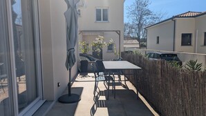 Un patio con tavolo e sedie, un ombrellone e vista su una casa vicina.