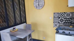 Un coin repas avec une table et des chaises, une horloge décorative au mur et un pare-feu en carreaux.