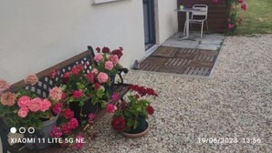 Un bâtiment doté d’une fenêtre, d’une porte et d’un banc agrémenté de pots de fleurs.