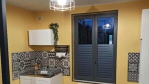 Une cuisine de taille réduite, dotée d’une fenêtre, d’un radiateur et d’un luminaire suspendu.