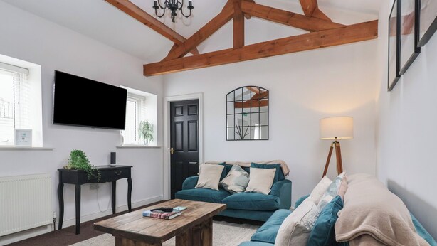 Ein Wohnzimmer mit Couchtisch aus Holz, Salons in Türkis, einem Fernseher und einer Lampe.