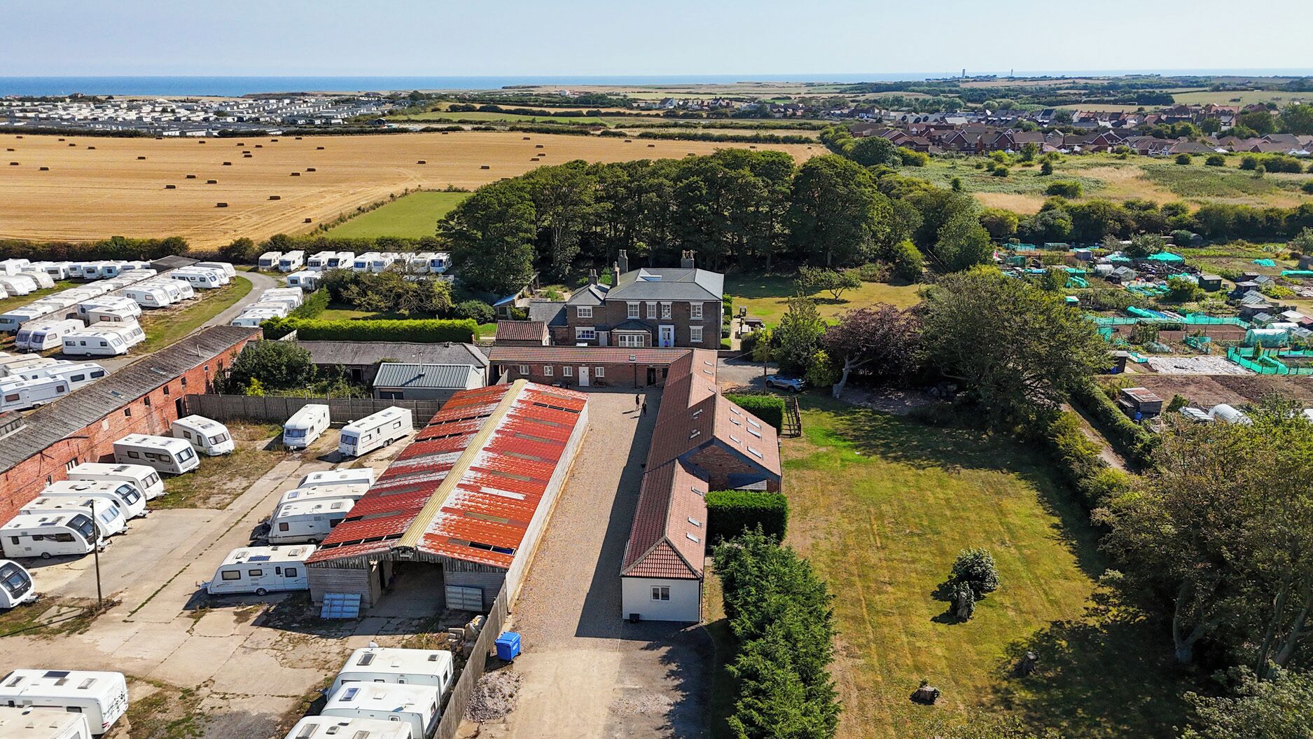 A caravan park with multiple caravans and a large building with a red roof.