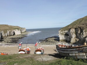 A coastal scene with boats, cliffs, and the sea. - Gannet (Bridlington)