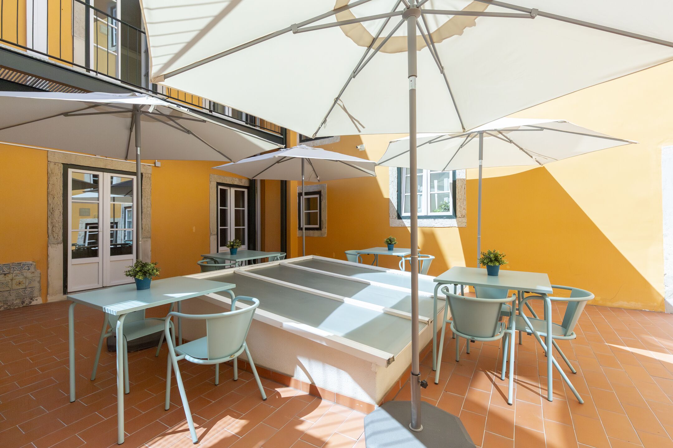 A terrace with outdoor seating, umbrellas, and a tiled floor.