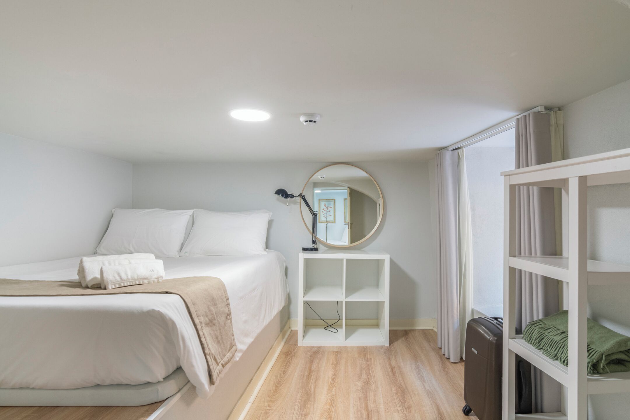 Une chambre à coucher avec un lit, une table de chevet avec une lampe, un miroir et une armoire.