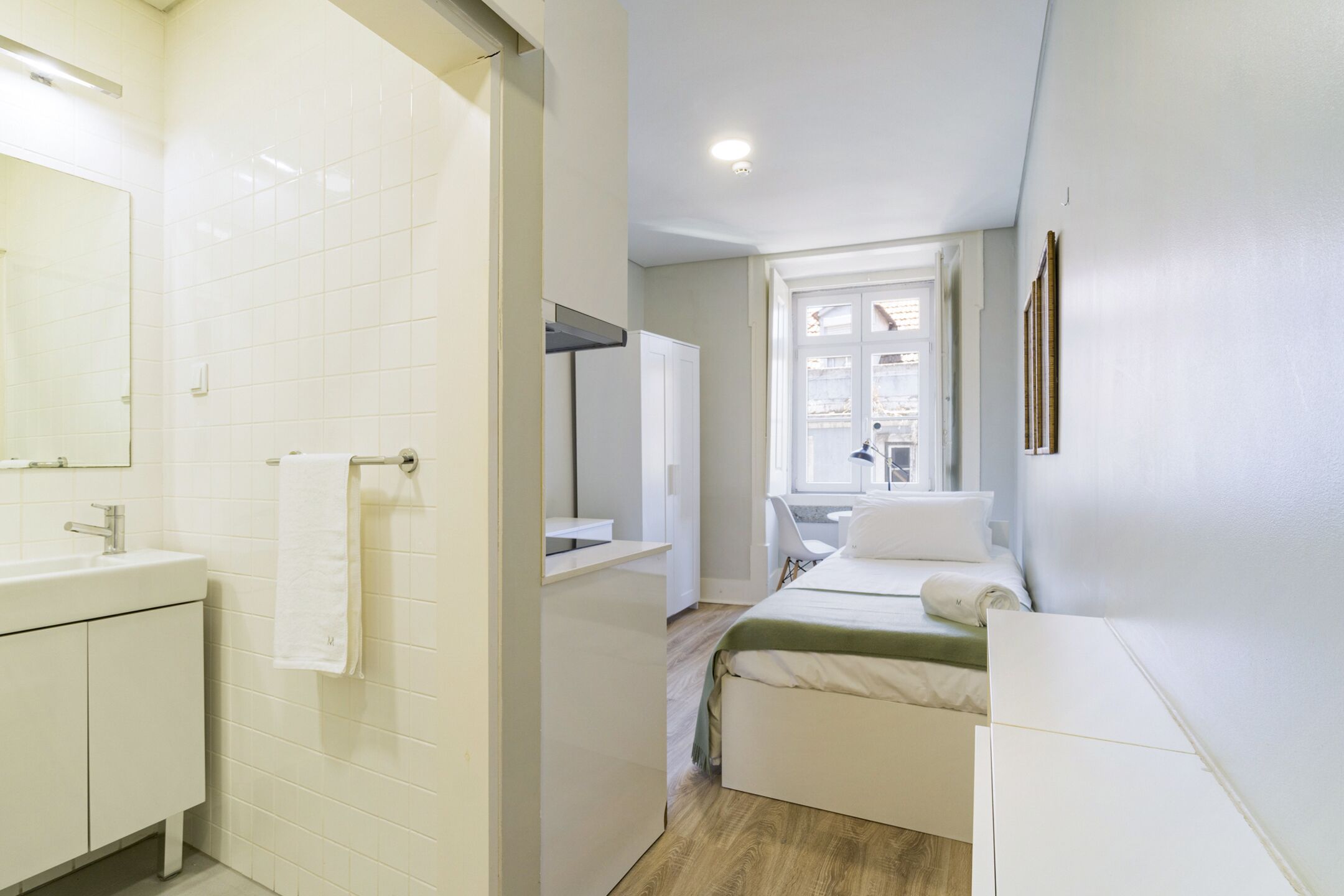 Quarto de hotel moderno com banheiro, cama e janela.