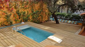 A rectangular pool with a wooden deck, surrounded by a wall with climbing plants. - Metropolitan Lisbon Janelas Verdes (Lisbon)