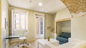 A modern living room with a glass desk, white sofa, and a blue couch. - Metropolitan Lisbon Janelas Verdes (Lisbon)