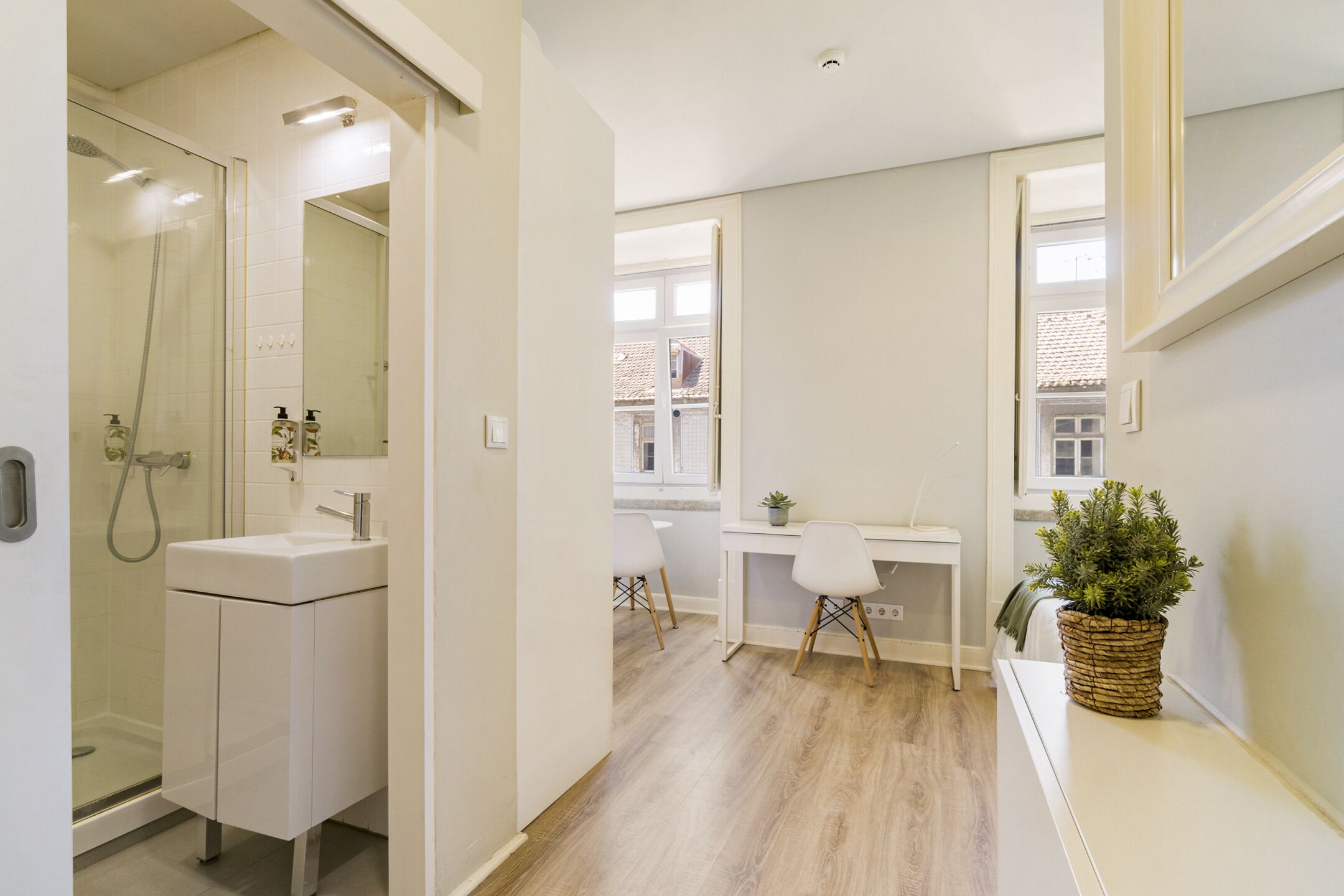 Une salle de bain moderne équipée d’une douche, d’un lavabo et d’un bureau avec une chaise.