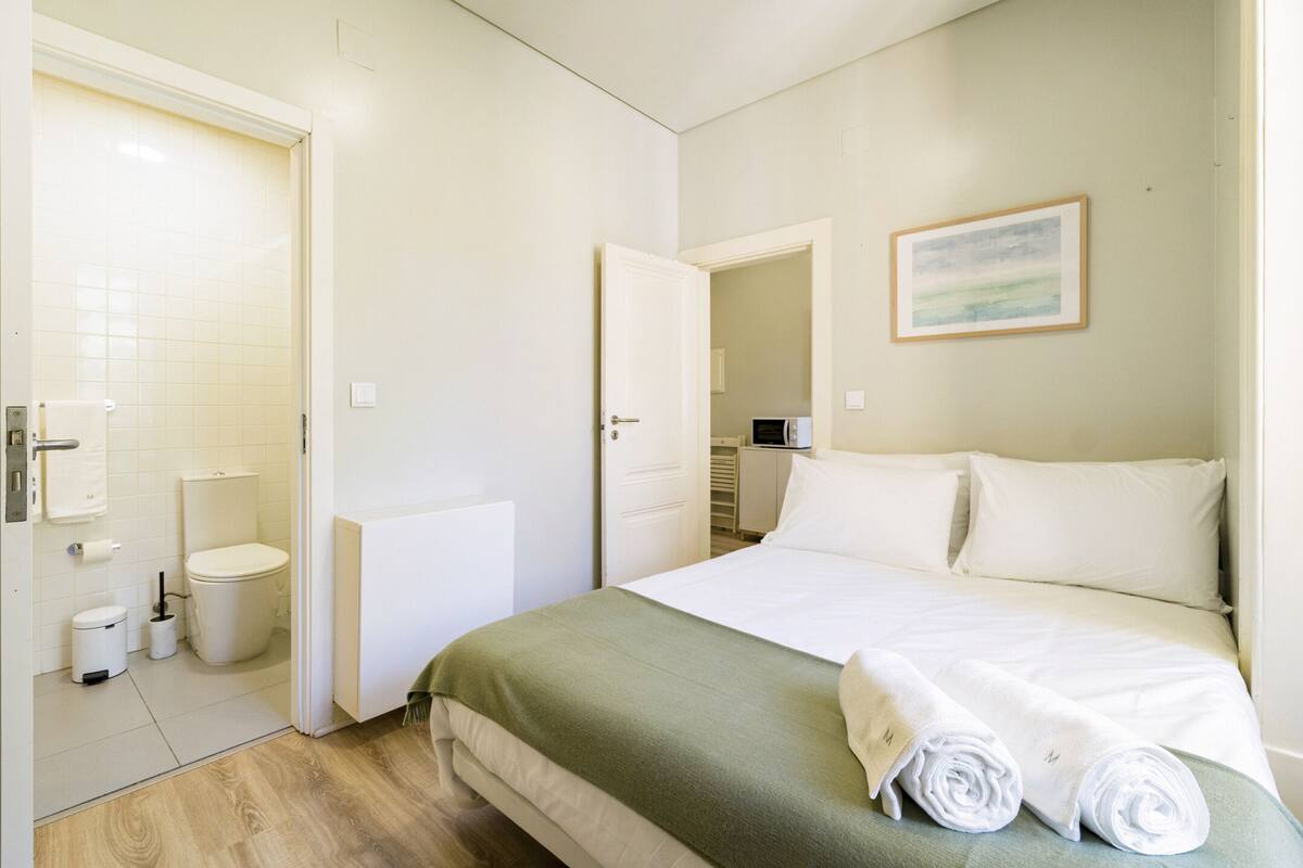 Een hotelkamer met een bed, een badkamer en een schilderij aan de muur.