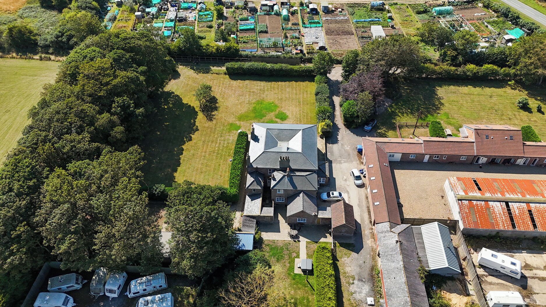 Vista aérea de una zona residencial que incluye una casa grande, varias casas más pequeñas y un campo.