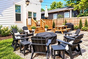 An outdoor patio with Adirondack chairs, a round table, and a barbecue grill. - Your 5‑Bedroom, 4‑Bath Retreat, Comfort, Style & Fun for Groups (Indianapolis)