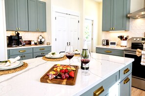 A kitchen with a marble countertop, a wine bottle, and a fruit platter. - Your 5‑Bedroom, 4‑Bath Retreat, Comfort, Style & Fun for Groups (Indianapolis)