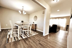 A dining area with a table and chairs, a chandelier, and a rug.