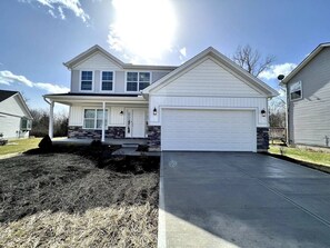 A two-story house with a garage, a front porch, and a driveway.
