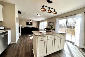 A spacious kitchen with a large island, white cabinetry, and a dining area with a view.