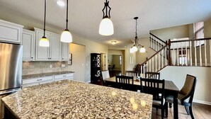 A kitchen with granite countertops, stainless steel appliances, and pendant lighting.