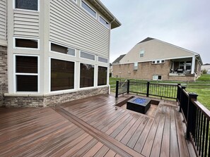 A wooden deck with a fire pit, a brick house with a garage, and a second-story balcony. - Large Executive Home In Lebanon Golf Community (Lebanon)