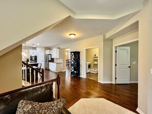 A spacious living area with a wooden staircase, a kitchen in the background, and a door leading to another room. - Large Executive Home In Lebanon Golf Community (Lebanon)