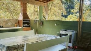 Una cucina esterna rustica con forno a mattoni, lavello e fornello.