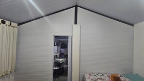 Una stanza con soffitto a falde, un letto con copripiumino floreale, una testiera in legno e un piccolo tavolo con sedie sullo sfondo.
