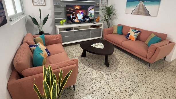 Un salon avec deux canapés, une table basse et un téléviseur posé sur un meuble en bois.