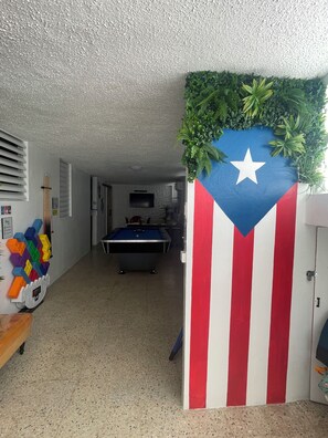 A room with a pool table, a colorful wall decoration, and a door with a flag design. - Fajardo Family Vacation Home + Solar Backup + Game Room (Fajardo)