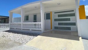 Un bâtiment moderne doté d’un porche abrité, d’un garage et d’un petit espace extérieur recouvert de gravier.
