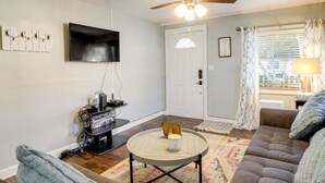 A living room with a sofa, a coffee table, a TV, and a door with a window. - Savannah Home w/ Yard ~ 3 Mi to Downtown! (Savannah)