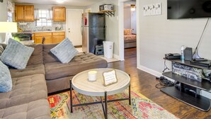 A living room with a sectional sofa, a coffee table, a TV, and a kitchen in the background. - Savannah Home w/ Yard ~ 3 Mi to Downtown! (Savannah)
