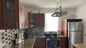 Una cocina moderna con armarios de madera, un refrigerador de acero inoxidable, horno empotrado y encimera de granito.
