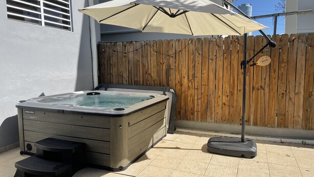 Un jacuzzi con cubierta de madera, cerco de madera y sombrilla.